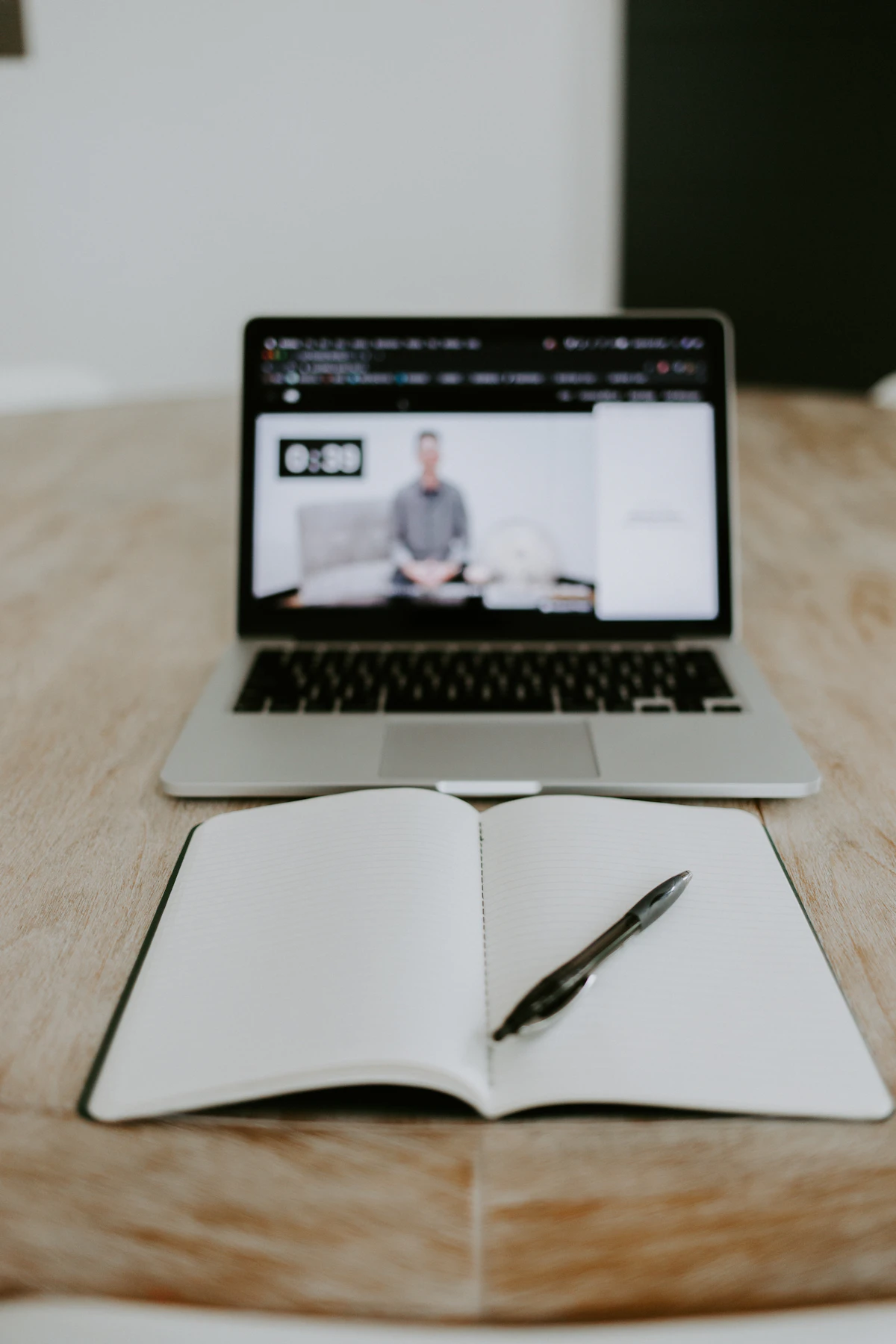 Laptop open on a desk during a video consultation, notebook and pen alongside